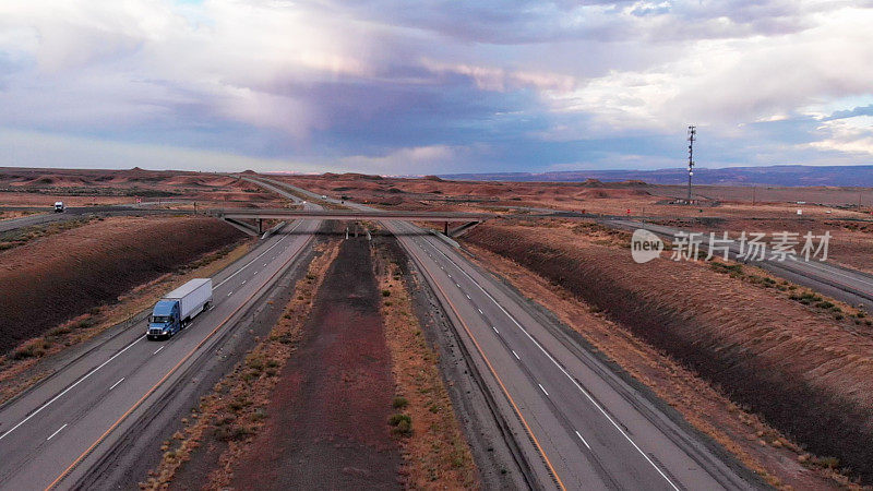 Long Haul Freight Hauler Semi-Truck and Trailer Traveling on a Four-Lane Highway in a desolate desert at dusk or dawn